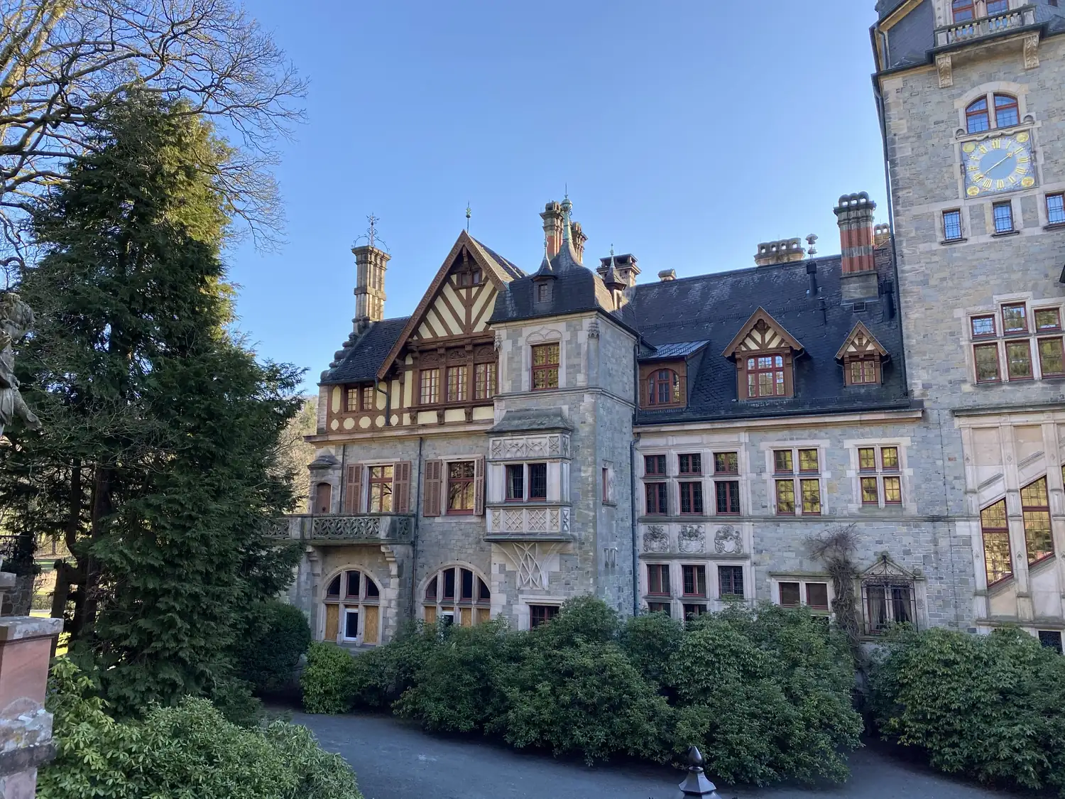 Detail der Fassade von Schloss Ramholz mit Fachwerkgiebel, Steinerker, Schornsteinen und Uhrturm
