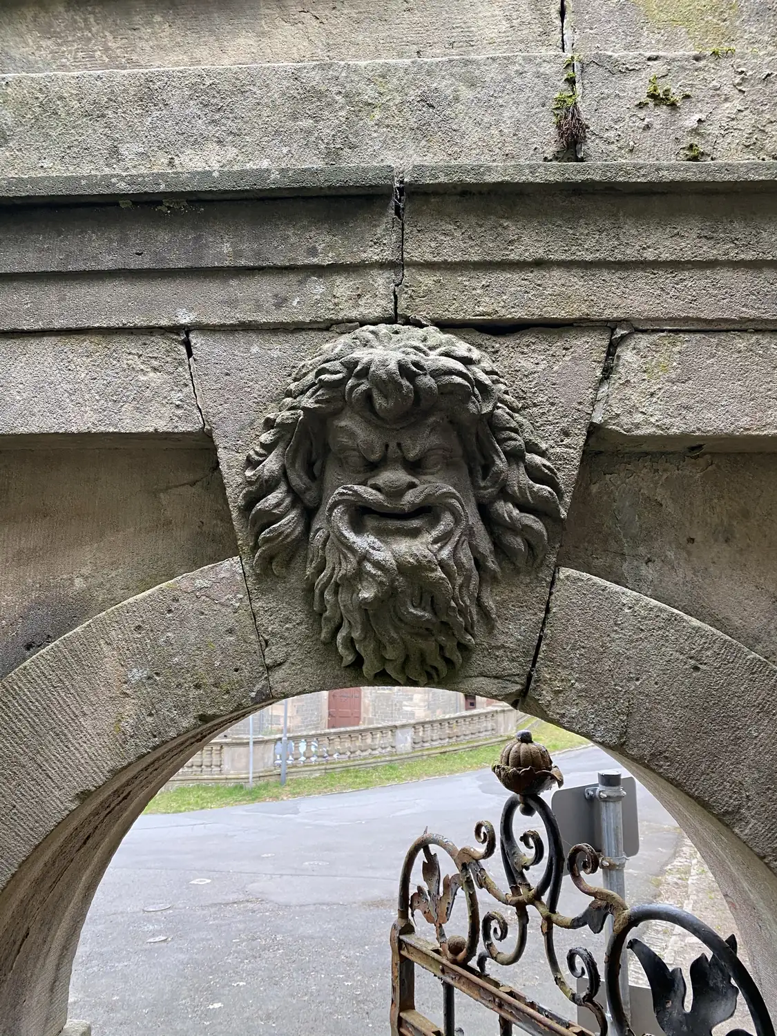 Steinerner Maskaron mit Bart und wildem Haar im Schlussstein eines Torbogens in Ramholz