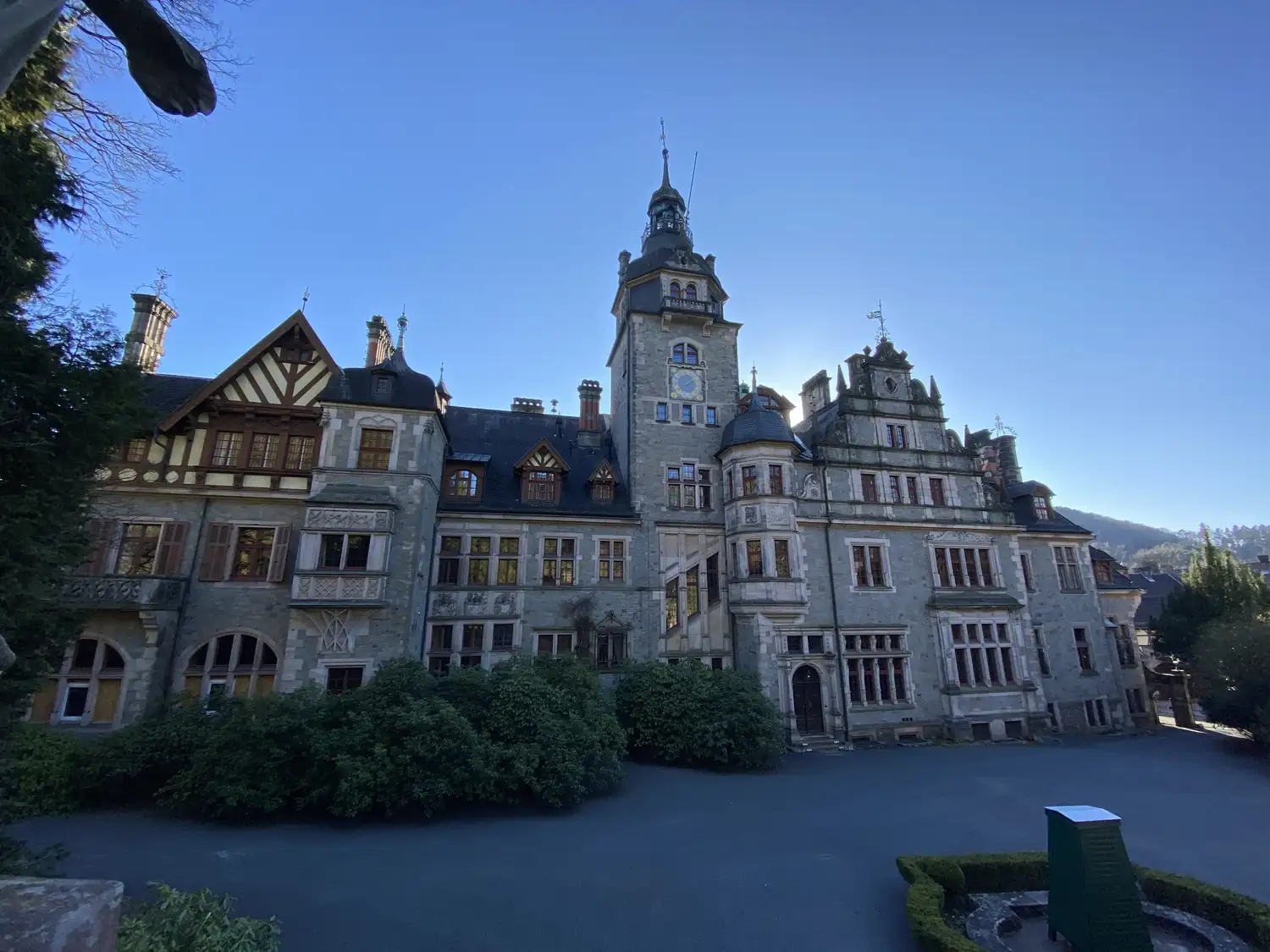 Schräge Gesamtansicht von Schloss Ramholz mit Uhrturm und Volutengiebel im Gegenlicht